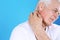 Senior man scratching neck on color background. Allergy symptom