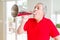 Senior man shouthing excited through vintage metal megaphone