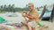 Senior man sits on the beach and making flute by hands.