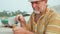 Senior man sits on the beach and making flute by hands, close-up.