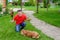 The senior man is sitting on the grass with shish kebab and a plate with vegetables