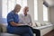 Senior man sitting looking at photo album with care nurse