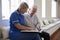 Senior man sitting looking at photo album with care nurse