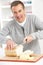 Senior Man Slicing Bread In Kitchen