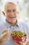 Senior Man Smiling At Camera And Eating Salad