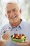 Senior Man Smiling At Camera And Eating Salad