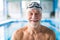 Senior man standing in an indoor swimming pool.