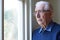 Senior Man Suffering From Depression Looking Out Of Wi