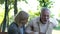 Senior man suffering sharp back pain, walking in park, caring wife helping him