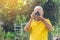 Senior man taking a photo by a digital camera while standing in the park. An elderly Asian man wears a yellow shirt be happy when