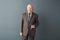 Senior man teacher studio standing isolated on gray holding glasses looking camera confident