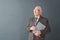 Senior man teacher wearing glasses studio standing isolated on gray holding book looking aside thoughtful