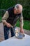 Senior man using manual grinder to grind up fresh razor clams for chowder, catch pan, and table