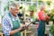 Senior man using tablet computer while wife working at greenhouse