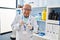 Senior man wearing scientist uniform holding sample plant with tweezers at laboratory