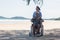 senior man on wheelchair and elderly woman couple smiling on sand of the beach