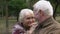 Senior man and woman admiring each other sitting on bench in park, close-up