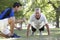 Senior Man Working With Personal Trainer In Park