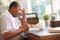 Senior Man Writing Memoirs In Book Sitting At Desk