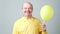 Senior man with yellow balloon with helium in hand
