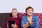 Senior married couple choosing movie on tv. Online broadcast from digital tablet on smart television. Elderly people at home