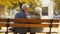 Senior married couple sits on the bench in park, wife touches husband& x27;s hair medium full shot