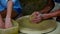 Senior master shows girl making clay pot on potter wheel