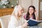 Senior mother and daughter read a book over a cup of tea