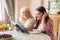 Senior mother and daughter read a book over a cup of tea