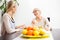 Senior mother and daughter talking and drinking tea in brightly lit dining room