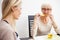 Senior mother and daughter talking and drinking tea in brightly lit dining room