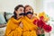 Senior mother and her adult daughter taking selfie with flowers using photo booth props at home. Mother`s day concept