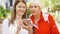 Senior mother and her young daughter standing on street using smartphone. Happy family together