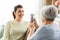 Senior mother photographing adult daughter at home