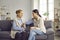 Senior mother talking to her grown-up young daughter while sitting on couch at home