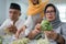 senior muslim couple and daughter making ketupat for eid fitr mubarak
