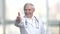 Senior old doctor in white coat and stethoscope shows thumb up.