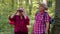 Senior old grandmother grandfather tourists hiking, traveling, exploring forest using binoculars