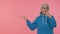 Senior old granny woman showing thumbs up and pointing at left on blank space, advertisement logo