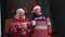 Senior old wife and husband talking, drinking tea near glowing xmas tree on Christmas in home room