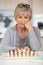 senior old woman playing chess moving pieces across chessboard