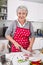 Senior or older woman with grey hair cooking in kitchen