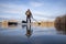 senior paddler on his paddleboard on lake in early spring in Colorado, frog perspective (partially submerged action