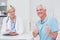 Senior patient gesturing thumbs up by doctor in clinic