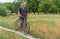 Senior peasant standing on a country road with old rusty bicycle