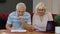 Senior pensioner couple checking and calculating domestic bills bank loan payment doing paperwork