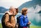 Senior pensioner couple hiking by lake in nature, holding hands.