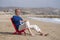 Senior pensioner sitting relaxed on the beach - retired old man on his 70s looking at the sea thoughtful and contemplative with