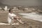 Senior pensioner sitting relaxed on the beach - retired old man on his 70s looking at the sea thoughtful and contemplative in