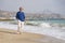 Senior pensioner taking a walk relaxed on the beach - retired old man on his 70s looking at the sea thoughtful and contemplative